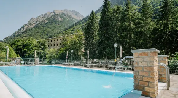 Piscina con acqua azzurra e montagne verdi sullo sfondo, un'oasi di relax alle terme di Valdieri.