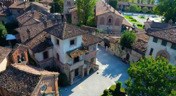 Un borgo fiabesco vicino Piacenza, con tetti in cotto e torri medievali, immerso nel verde.