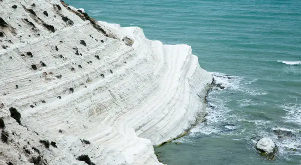 La scogliera bianca di Sicilia, con le sue stratificazioni calcaree, si tuffa nel mare turchese.