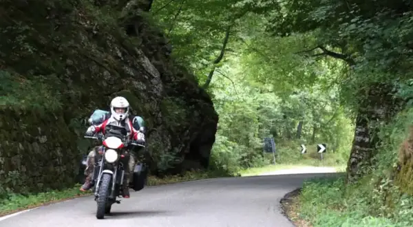 Motociclista in un percorso tortuoso tra rocce e alberi. Un'avventura di giri in moto in Emilia Romagna.