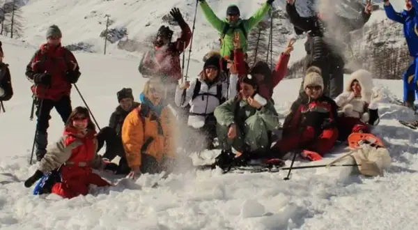 Un gruppo di amici si diverte con le ciaspolate in Val d'Aosta, tra risate e lanci di neve.