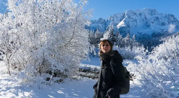 Donna con zaino in un paesaggio invernale innevato, montagne sullo sfondo. Val Saisera incanta con la sua bellezza.