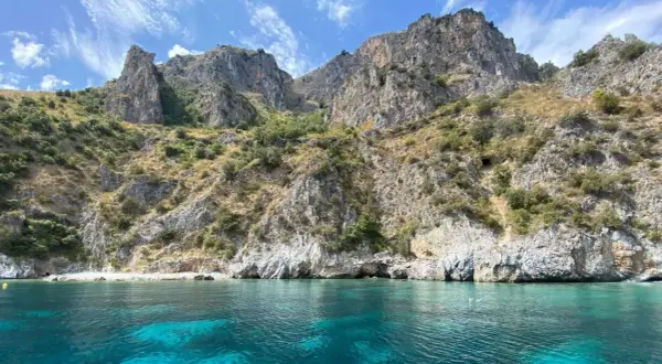 Paesaggi mozzafiato mare: scogliere rocciose ricoperte di vegetazione si tuffano in acque cristalline e turchesi.