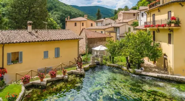Borgo pittoresco con case gialle e un ruscello cristallino. Un'ottima meta per scoprire cosa vedere vicino Assisi.
