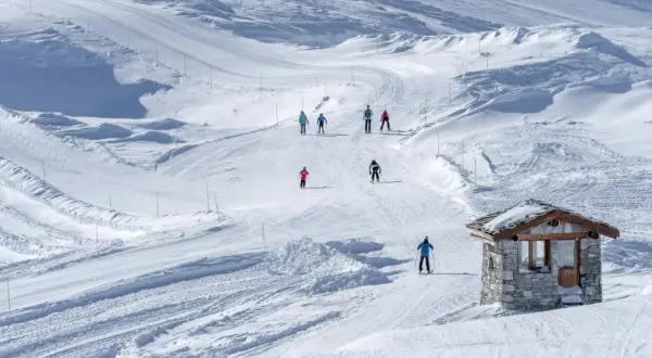 Sciare in un paesaggio innevato, perfetto per una settimana bianca in Piemonte. Piccola baita di pietra sulla pista.