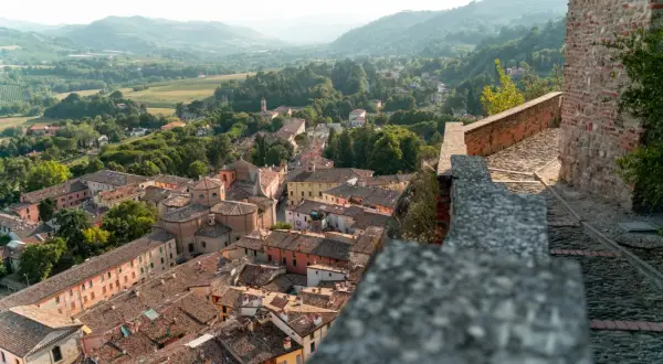 Panoramica di **borghi vicino Reggio Emilia** con tetti in cotto e colline verdi sullo sfondo.