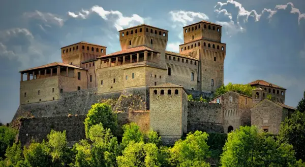 Roccastraordinaria di Torrechiara, un gioiello incastonato tra le colline di Parma, Emilia Romagna, con torri imponenti e un cielo drammatico.