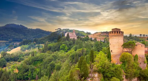 Brisighella, un borgo medievale in Emilia-Romagna, con la sua Rocca Manfrediana e la chiesa sulla collina, immerso nel verde.
