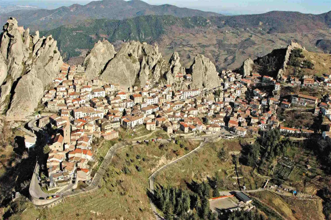 Un pittoresco borgo in Basilicata, aggrappato a rocce imponenti, con case dai tetti rossi che si estendono sul pendio.