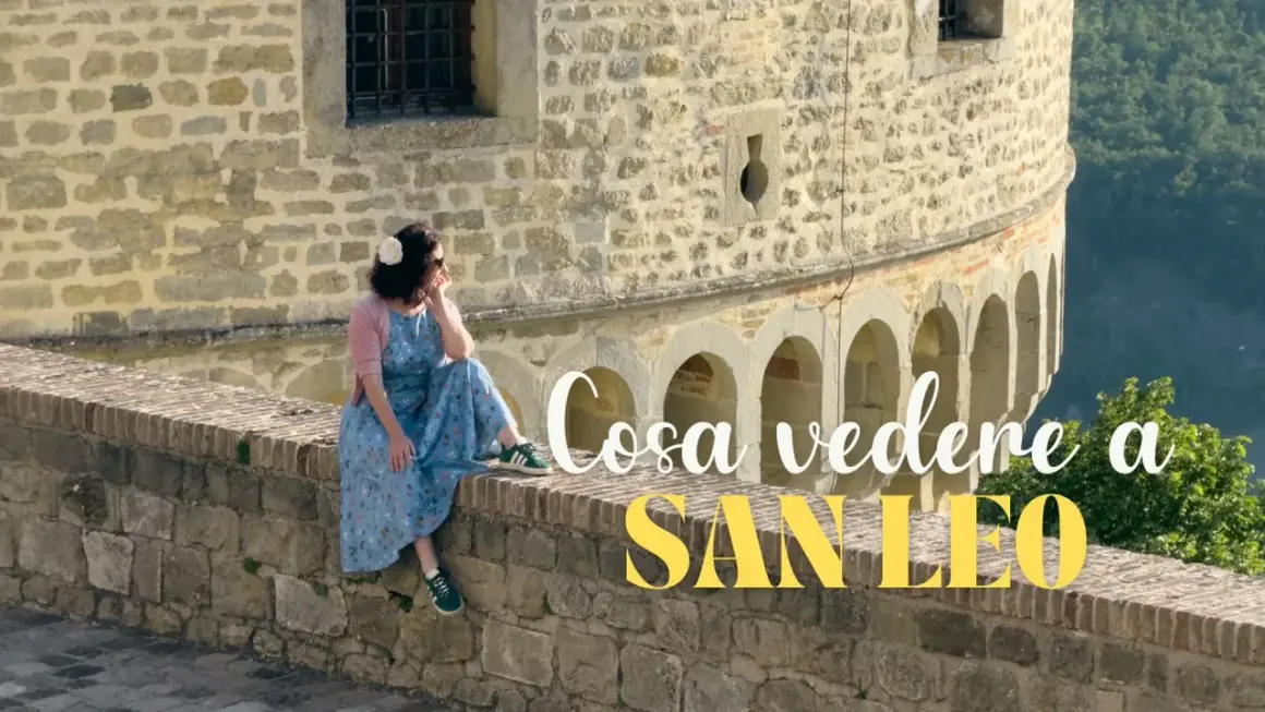 Donna seduta su un muretto di pietra a San Leo, con testo "Cosa vedere a San Leo".