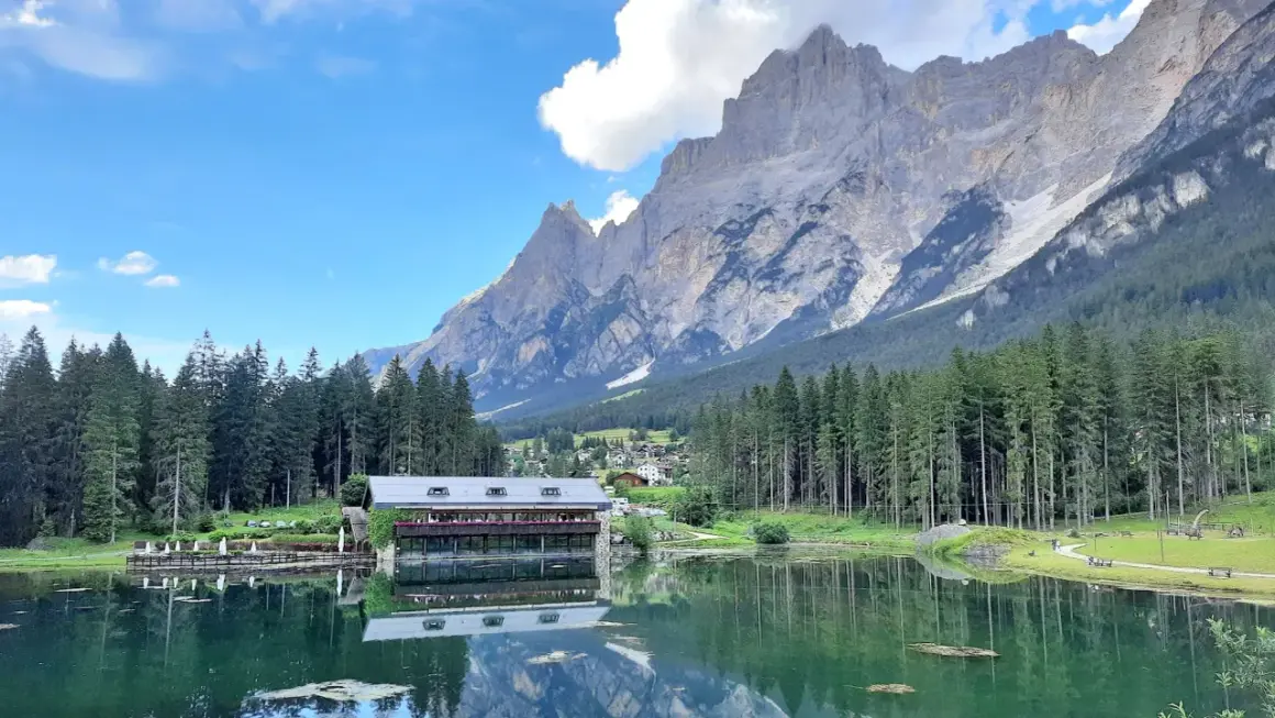 Lago alpino con rifugio e montagne maestose, ideale per passeggiate facili in Cadore.