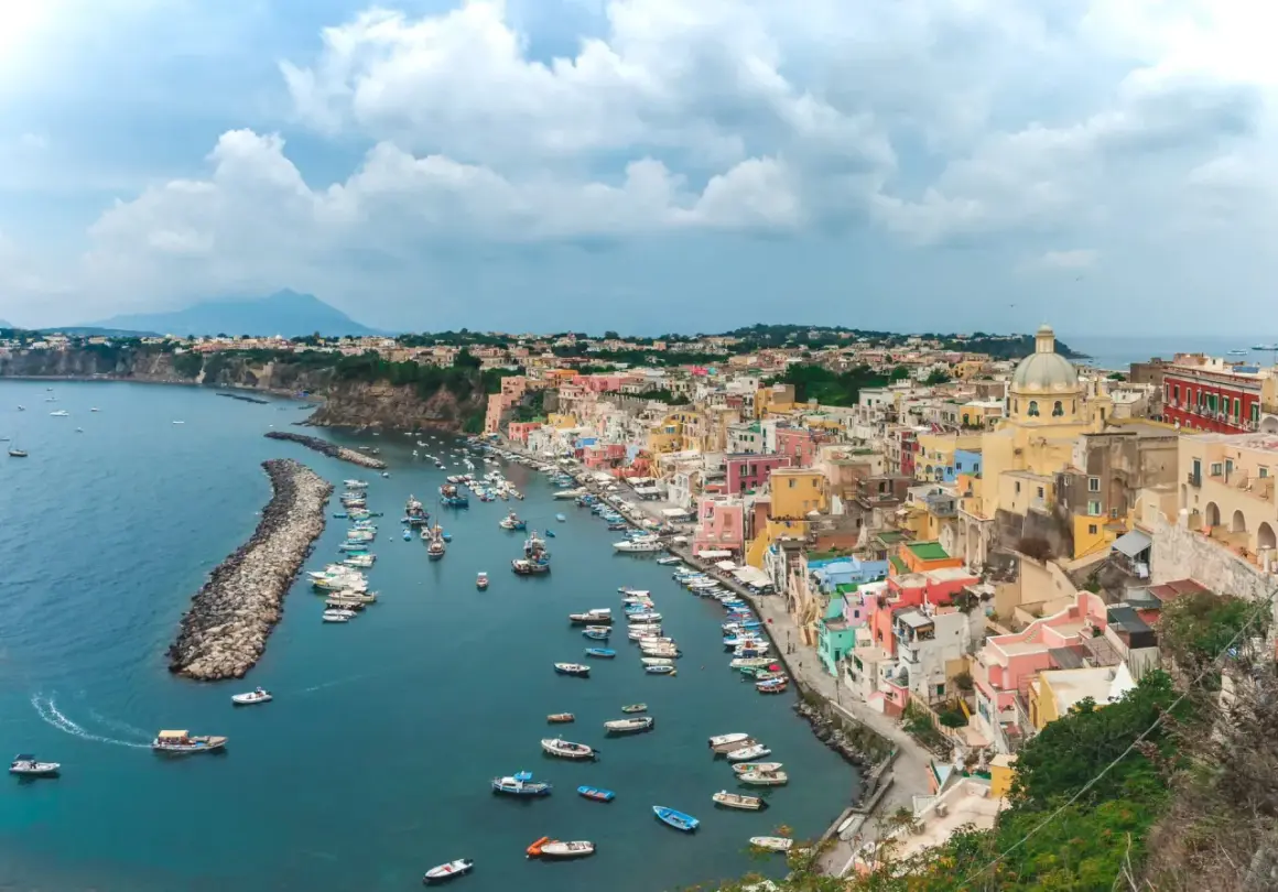 Un pittoresco borgo colorato sul mare vicino Napoli, con barche ormeggiate in un porto tranquillo e una vista mozzafiato.