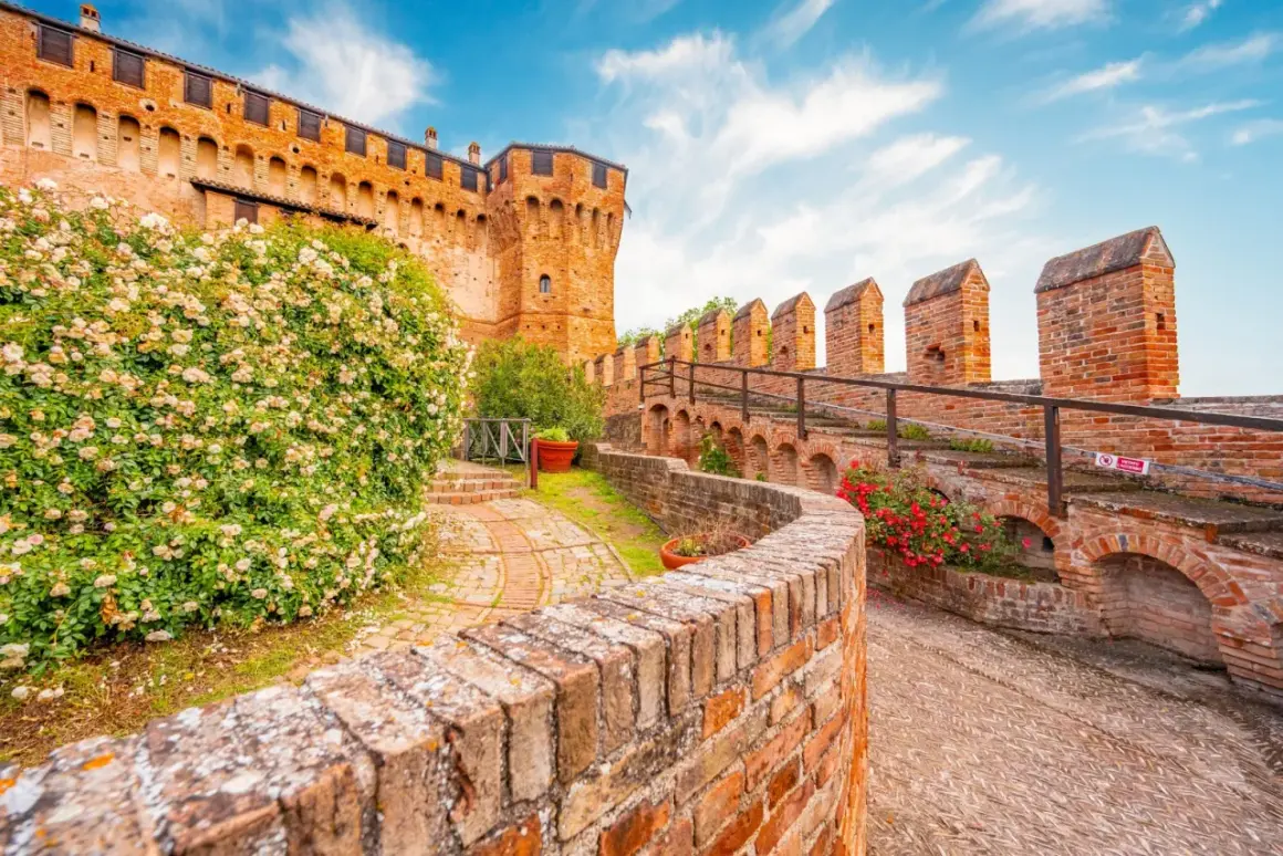 Un sentiero tra rose e mattoni rossi porta verso un castello, un assaggio dei 5 borghi più belli delle Marche.