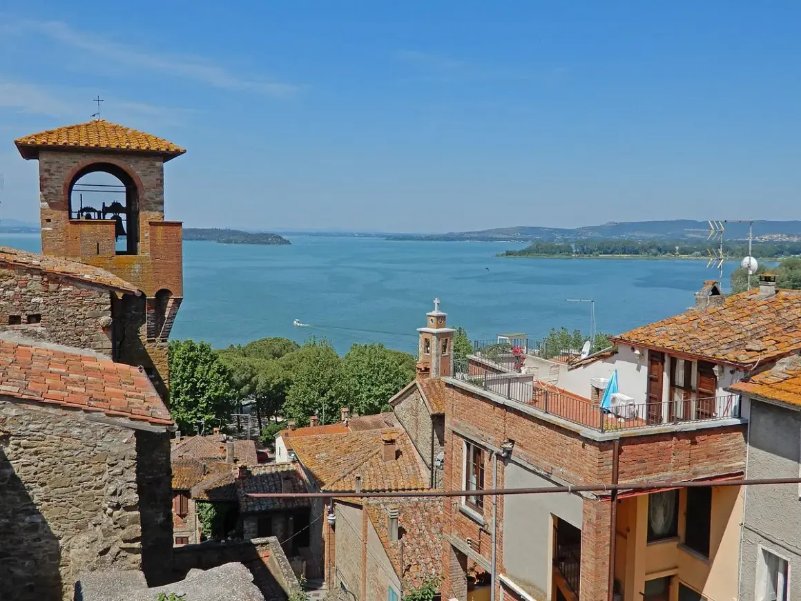 Vista panoramica di Passignano sul Trasimeno: campanile, tetti rossi e il lago azzurro. Ecco cosa vedere!
