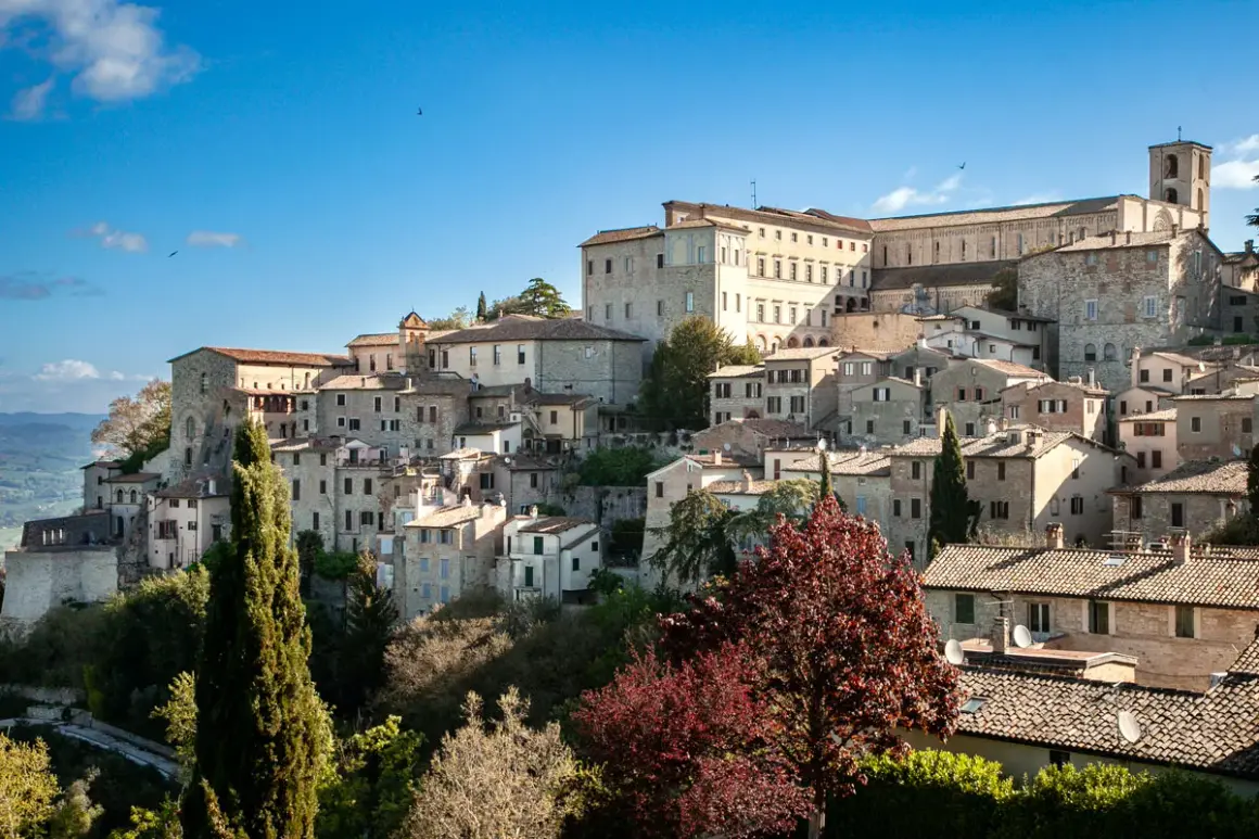 Un borgo medievale arroccato su una collina, con case in pietra e un imponente palazzo. Questo è dove si trova Todi, un gioiello umbro.
