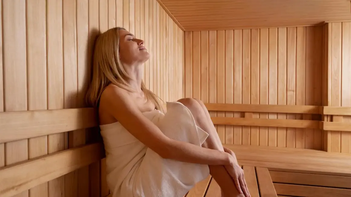 Donna rilassata in una sauna di legno, godendosi il calore. Un'esperienza rigenerante come le terme francescane.