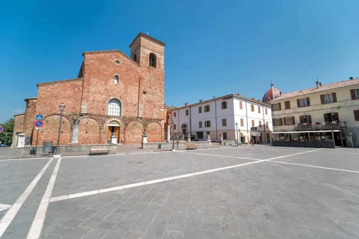 Piazza principale di Sarsina, dove si trova la Basilica di San Vincenzo Martire, con edifici storici e cielo azzurro.