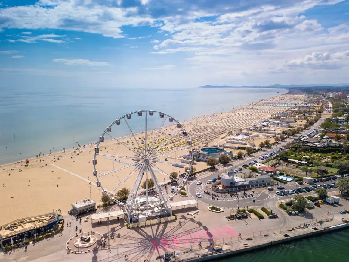 Ruota panoramica su una delle spiagge più belle dell'Emilia Romagna, con ombrelloni dorati e mare azzurro.
