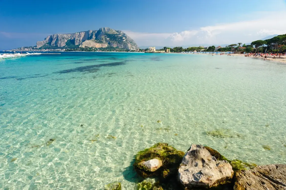 Splendido mare cristallino vicino Palermo, con la costa e il Monte Pellegrino sullo sfondo.