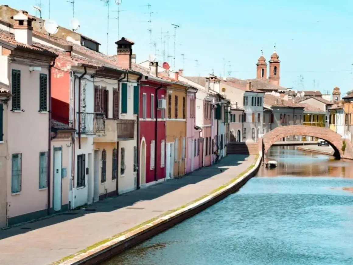 Comacchio: case colorate lungo il canale, un ponte ad arco e torri. Ideale per scoprire cosa vedere a Comacchio e dintorni in due giorni.