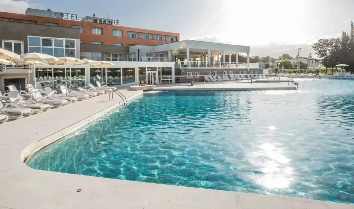Piscina con lettini e ombrelloni in un resort a Venturina Terme. Un'oasi di relax dove godersi il sole e l'acqua cristallina, un'esperienza quasi venturina terme kostenlos.
