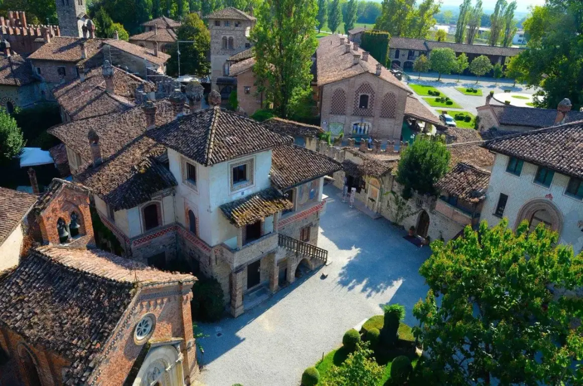 Un borgo fiabesco vicino Piacenza, con tetti in cotto e torri medievali, immerso nel verde.