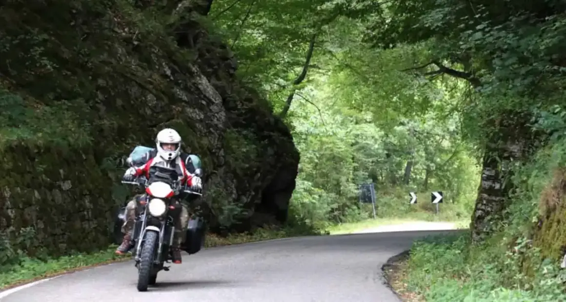 Motociclista in un percorso tortuoso tra rocce e alberi. Un'avventura di giri in moto in Emilia Romagna.