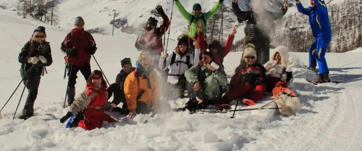 Un gruppo di amici si diverte con le ciaspolate in Val d'Aosta, tra risate e lanci di neve.