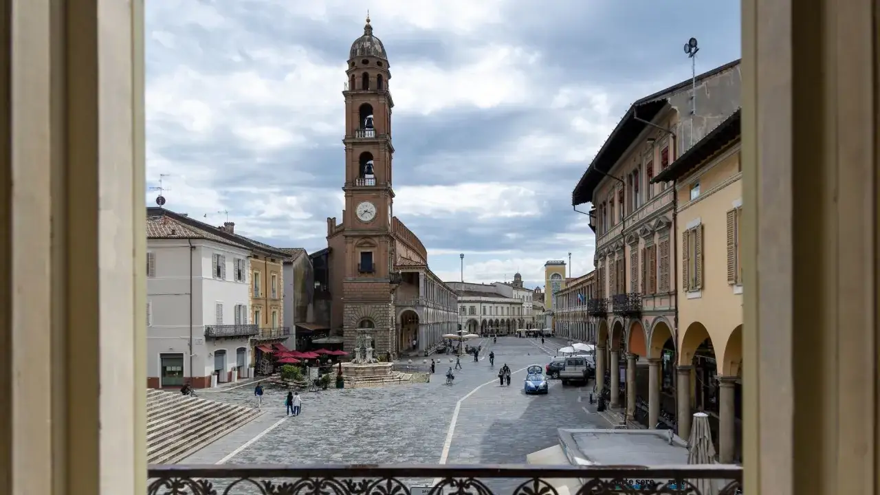 Piazza del Popolo a Faenza, Italia, con la torre civica e gli eleganti portici che incorniciano la piazza.
