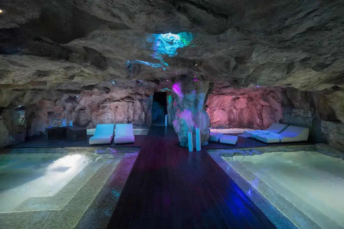Un'oasi di relax nelle terme Campania inverno: piscine riscaldate, lettini bianchi e luci soffuse in una grotta suggestiva.