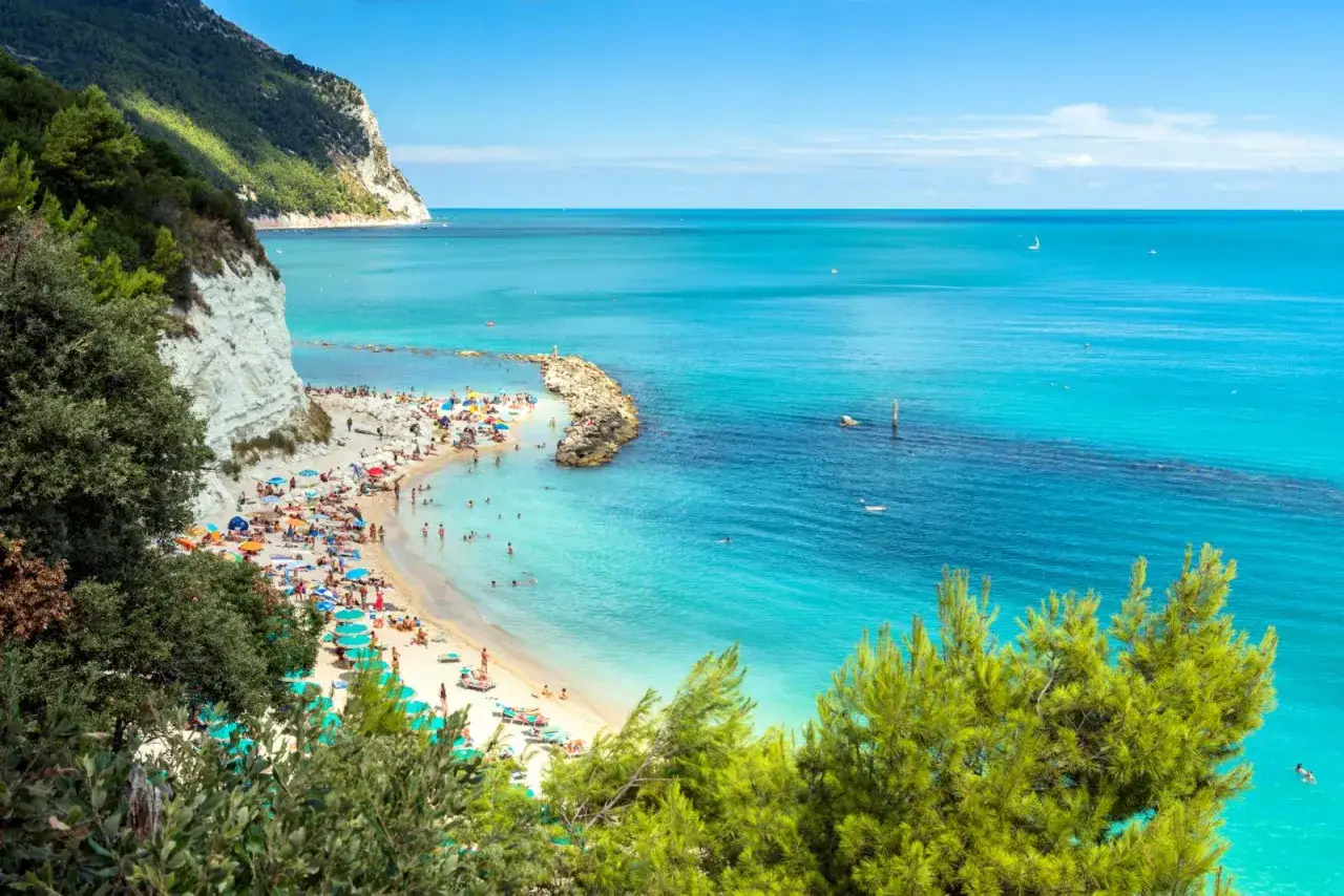 Spiaggia affollata con ombrelloni colorati e gente che si gode il sole e il mare cristallino dell'Abruzzo.