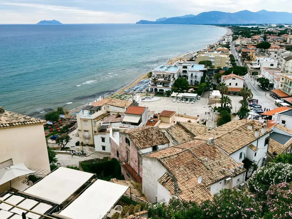 Vista panoramica di Sperlonga, dove si trova questo incantevole borgo affacciato sul mare azzurro, con case dai tetti rossi e una spiaggia attrezzata.