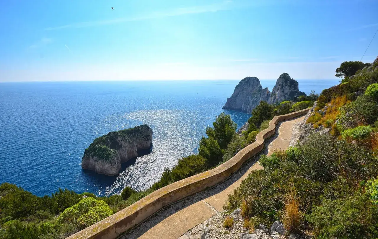 Sentiero panoramico a Capri a piedi, con vista sui Faraglioni e il mare blu scintillante.