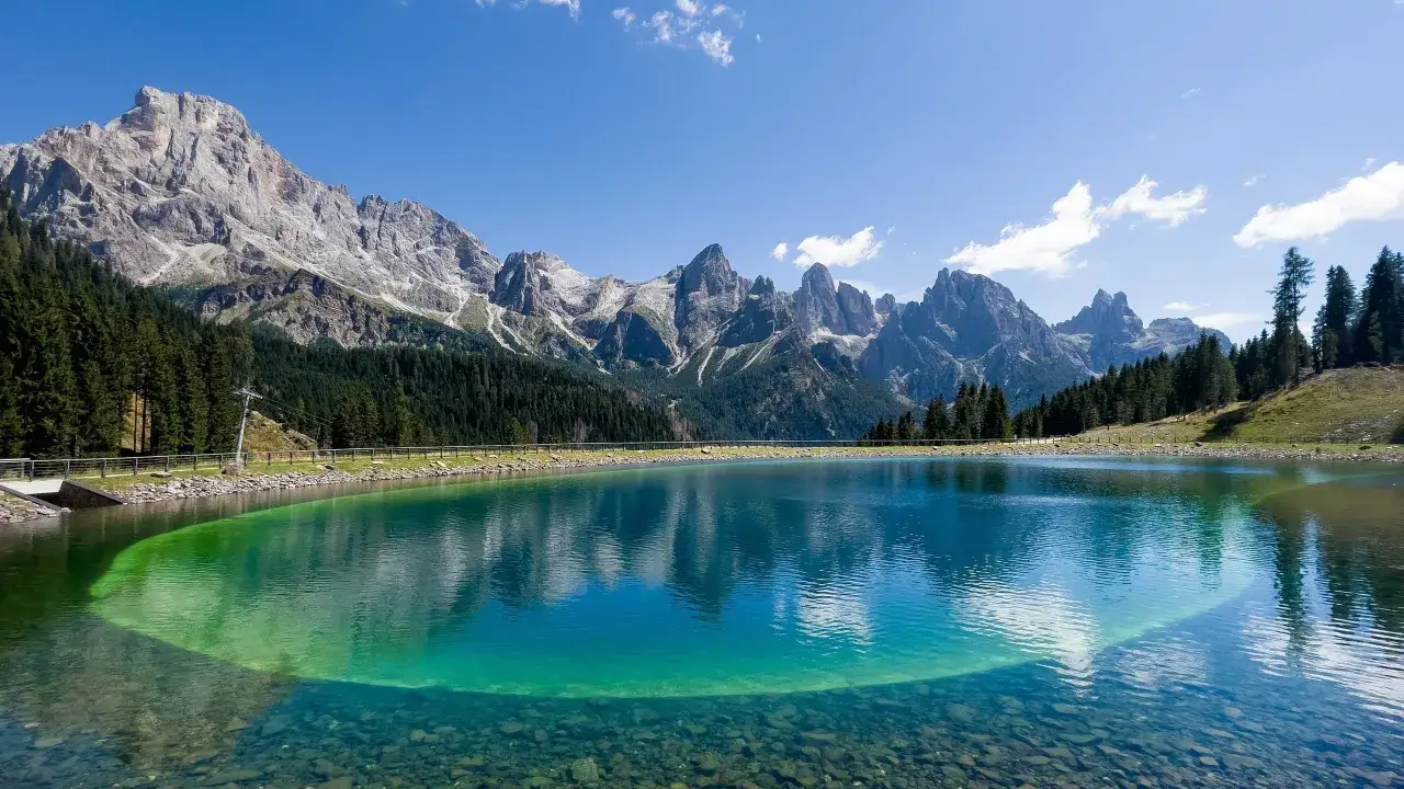 Lago alpino cristallino con montagne maestose sullo sfondo, ideale per passeggiate Trentino.