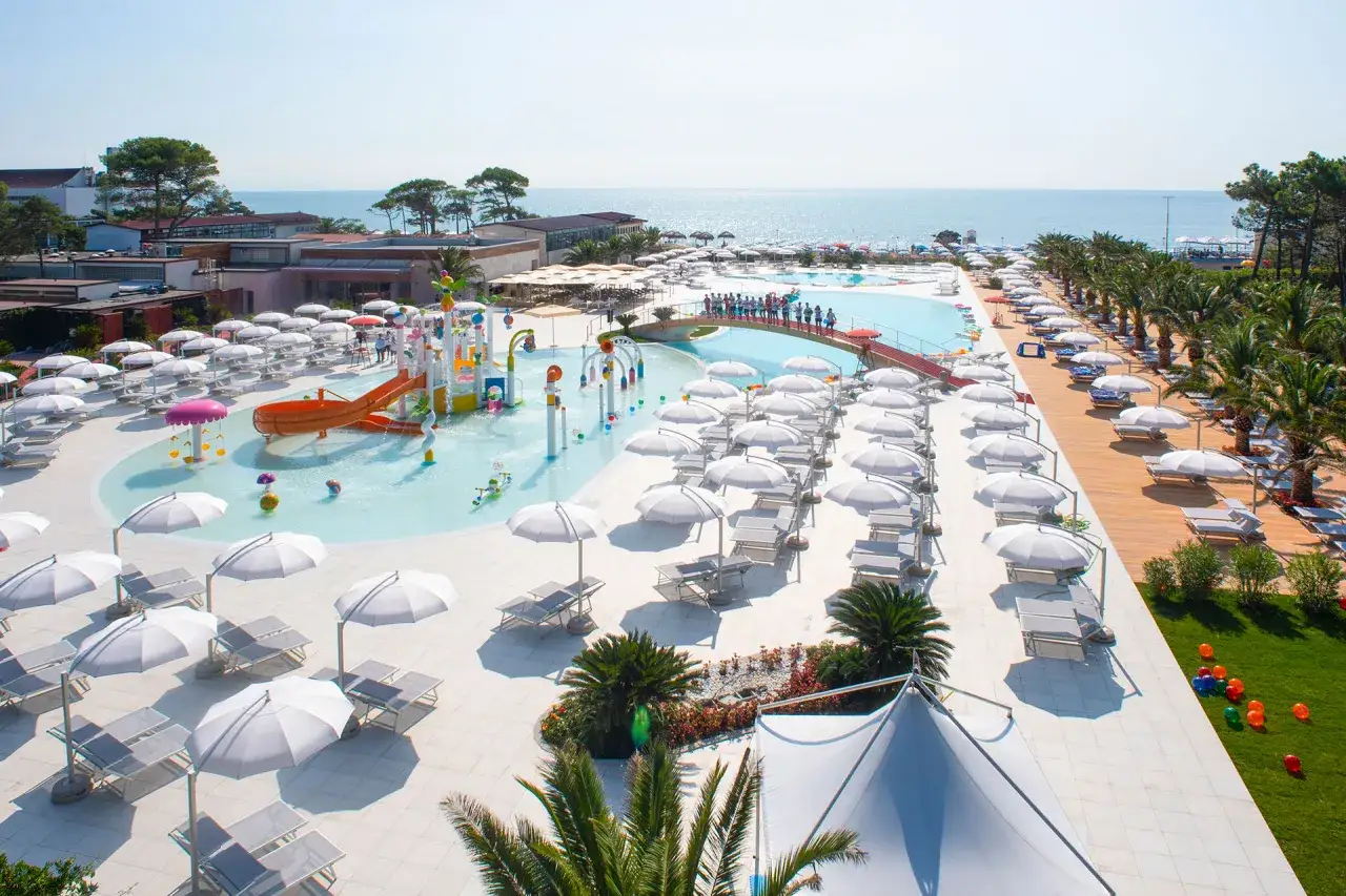 Un resort con piscine, scivoli acquatici e lettini prendisole, ideale per una vacanza alle terme Lignano.