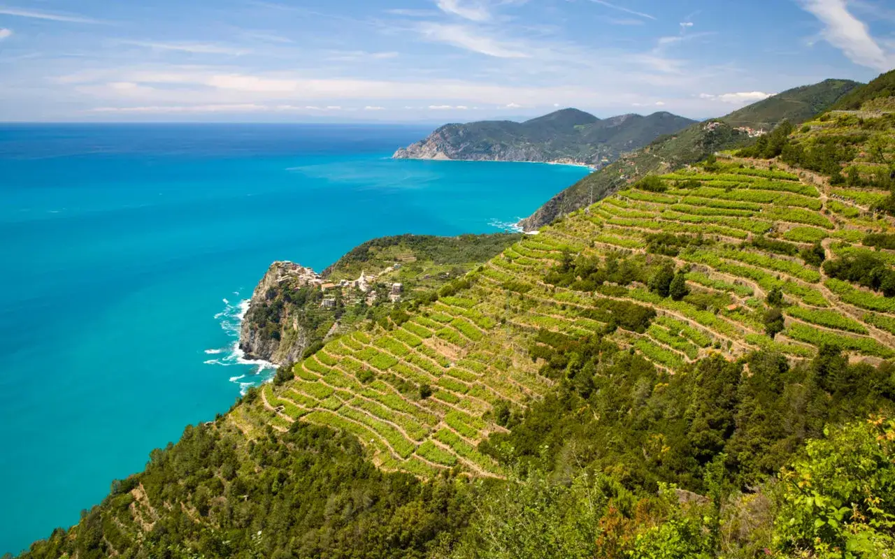 Terrazzamenti verdi scendono verso il mare turchese, un paesaggio da cartolina tra i posti belli in Liguria sul mare.