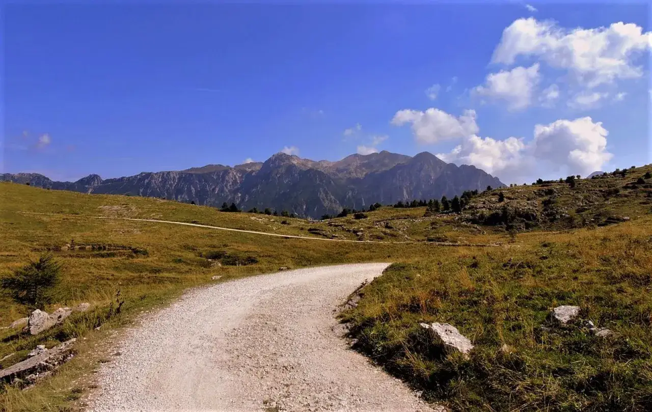 Sentiero sterrato tra colline verdi e montagne imponenti, un invito a scoprire cosa vedere in Valpolicella.