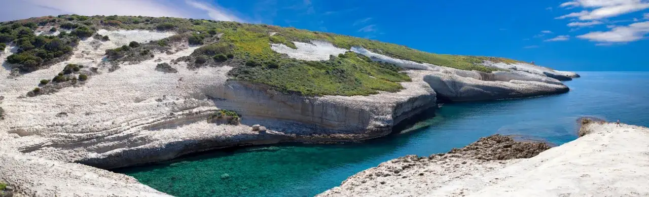 Scogliere bianche e verdi si tuffano in acque cristalline. Un angolo di paradiso con paesaggi mozzafiato e mare turchese.