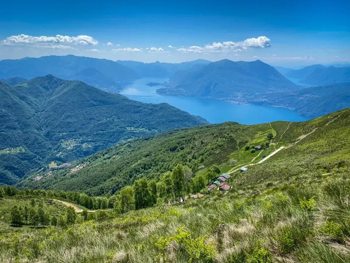 Panoramica di una montagna vicino Milano, a 1 ora di distanza, con un lago azzurro e case sparse.