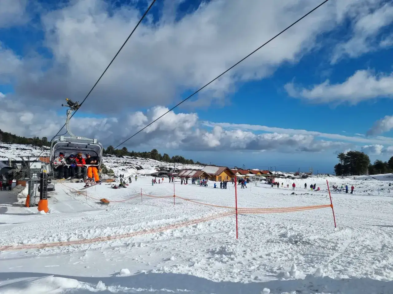Immagini di sciare sull'Etna: gente in seggiovia, piste innevate e rifugi. Un'avventura da non perdere, ma informati sui costi!