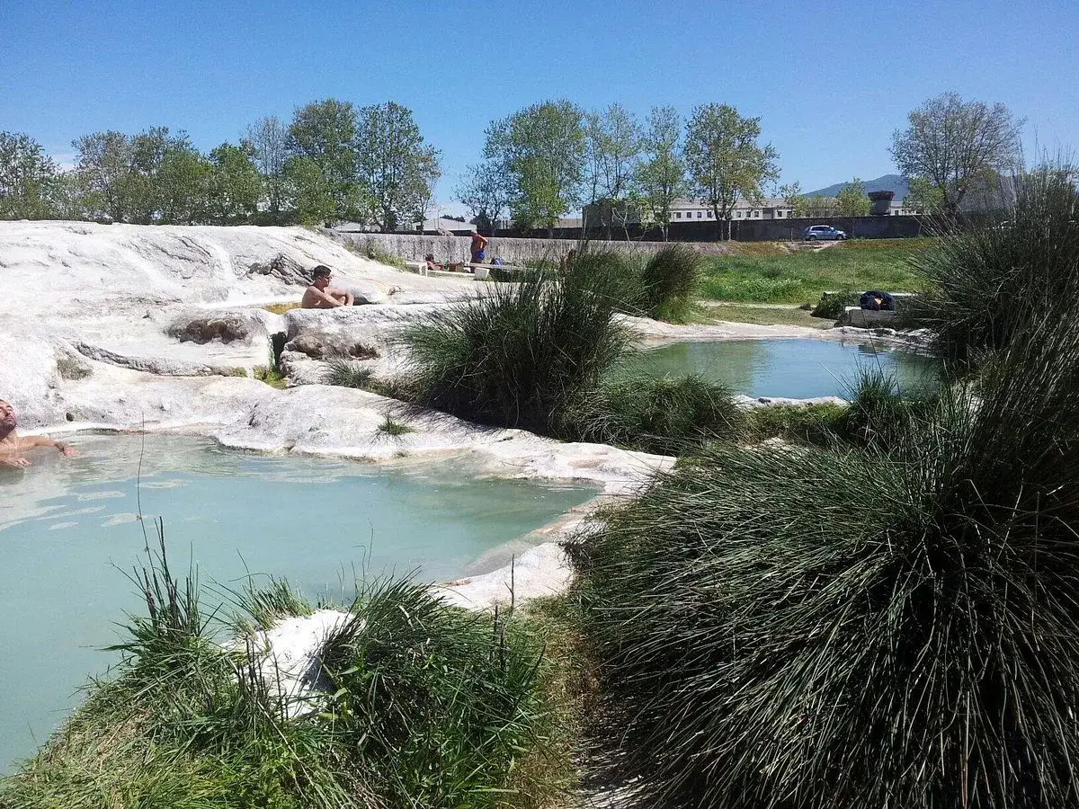 Relax in the piscine carletti, natural thermal pools surrounded by lush greenery and white rocks.