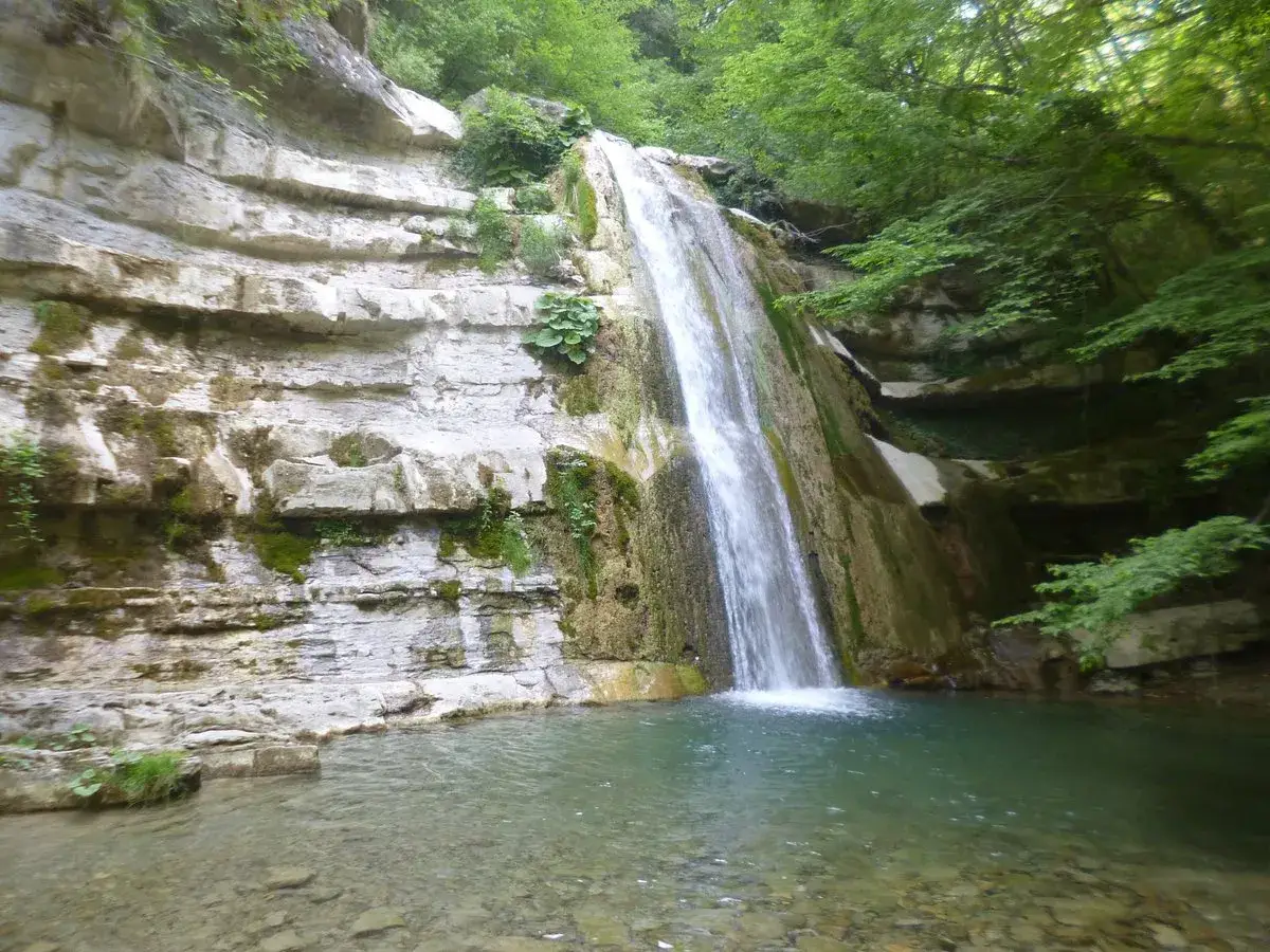 Cascata a San Benedetto in Alpe, un luogo incantevole da scoprire. Rocce stratificate e vegetazione rigogliosa circondano la cascata.