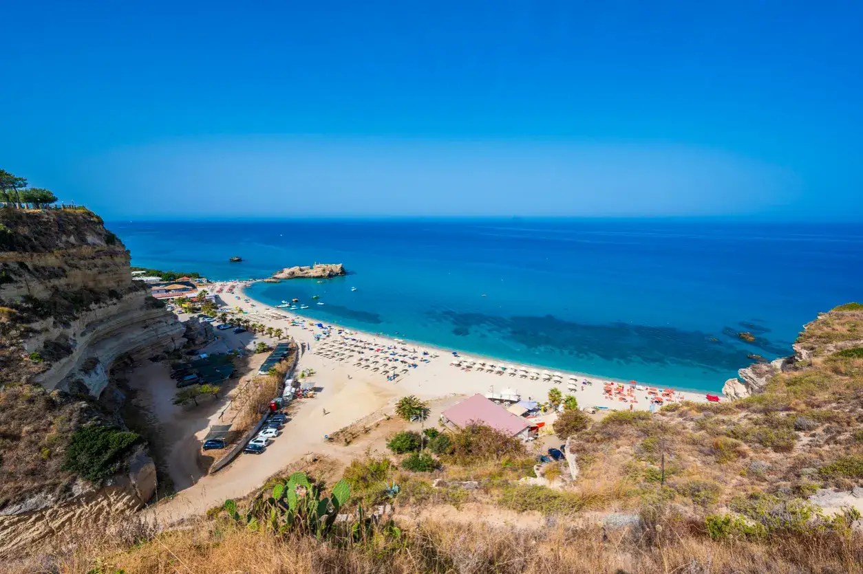 Vista dall'alto della Baia di Riaci, con spiaggia attrezzata, mare cristallino e scogliere. Ecco come arrivare!