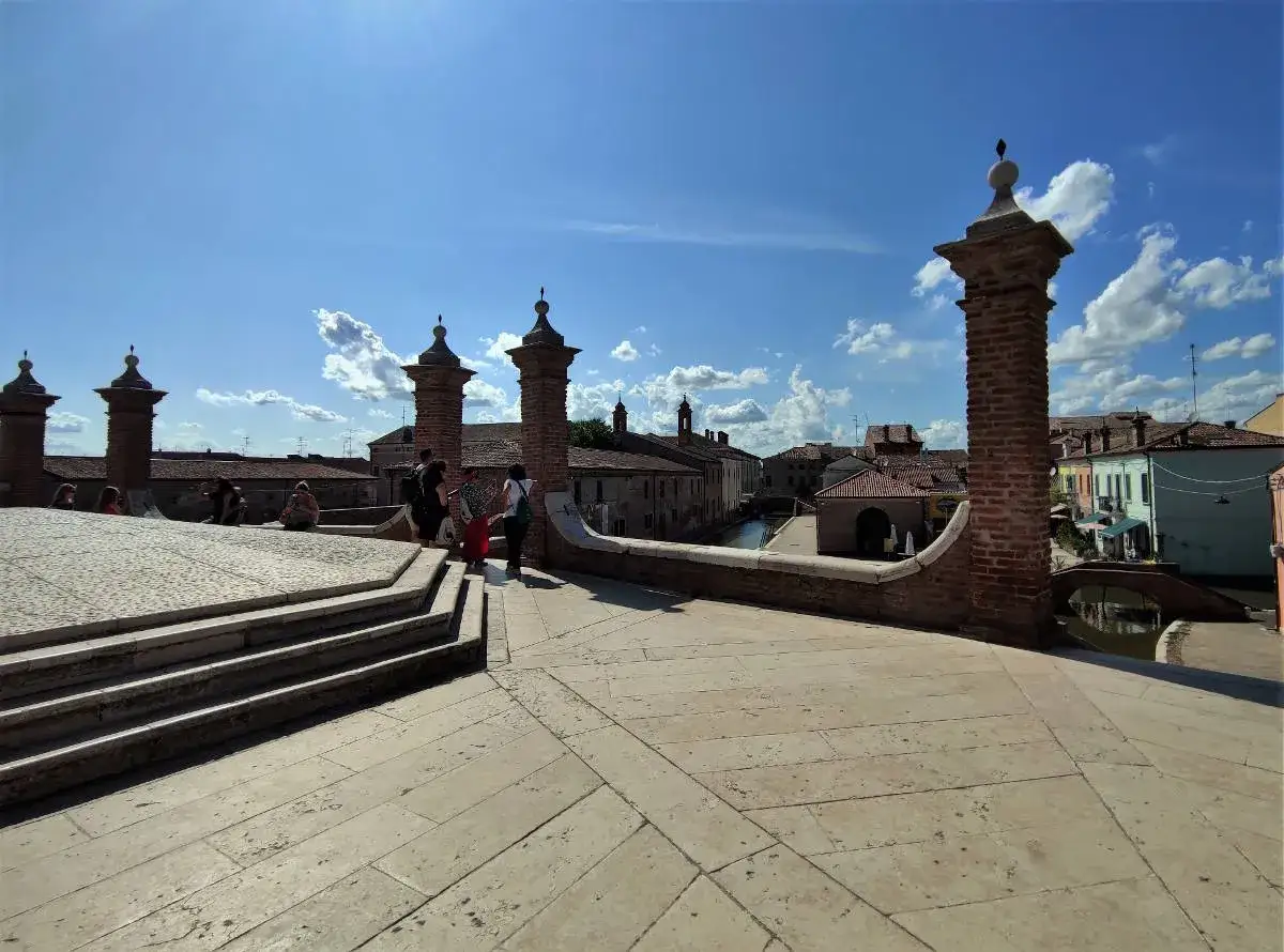 Ponte di Comacchio, ideale per scoprire cosa vedere a Comacchio e dintorni in due giorni. Canali, case colorate e cielo azzurro.