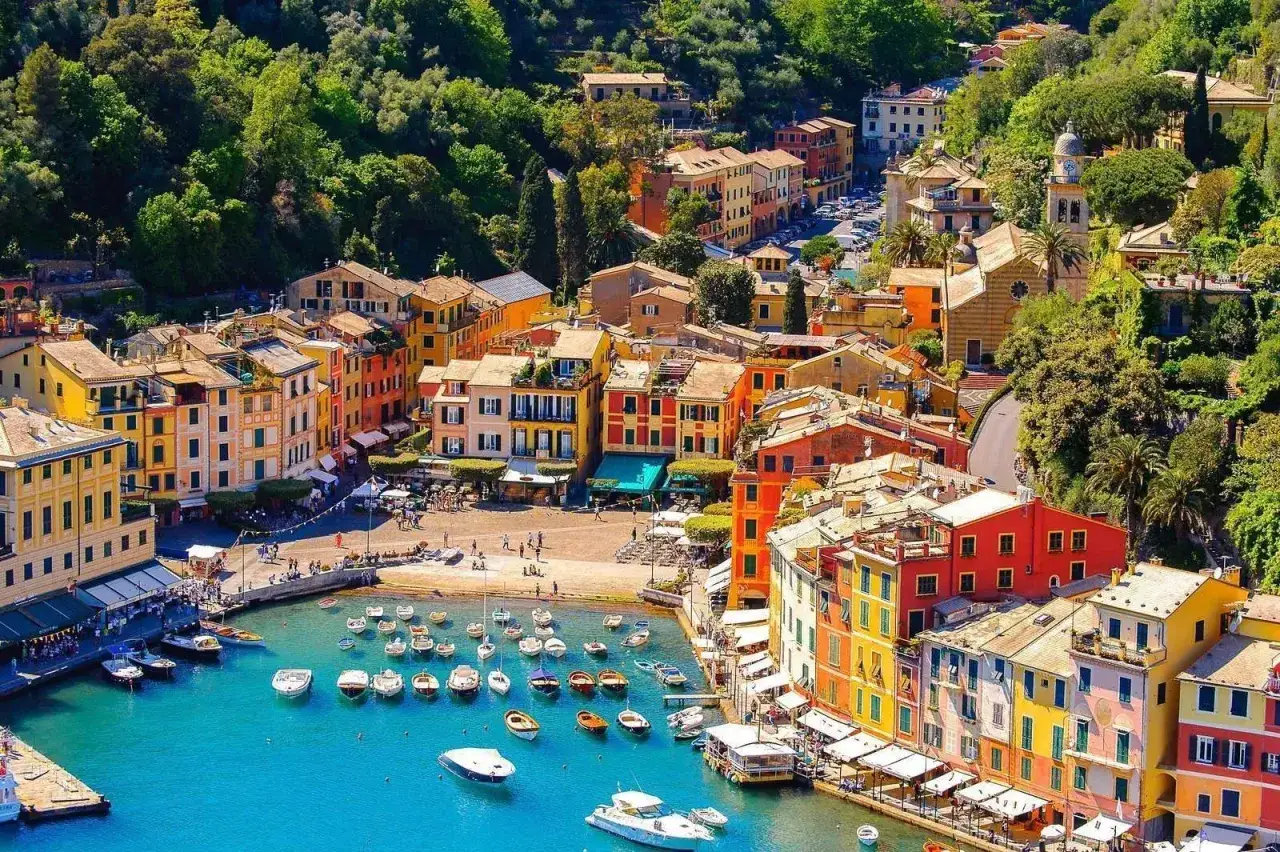 Portofino, incantevole borgo ligure, si rivela in tutta la sua bellezza con case colorate affacciate sul porto azzurro, dove barche e yacht riposano tranquilli.