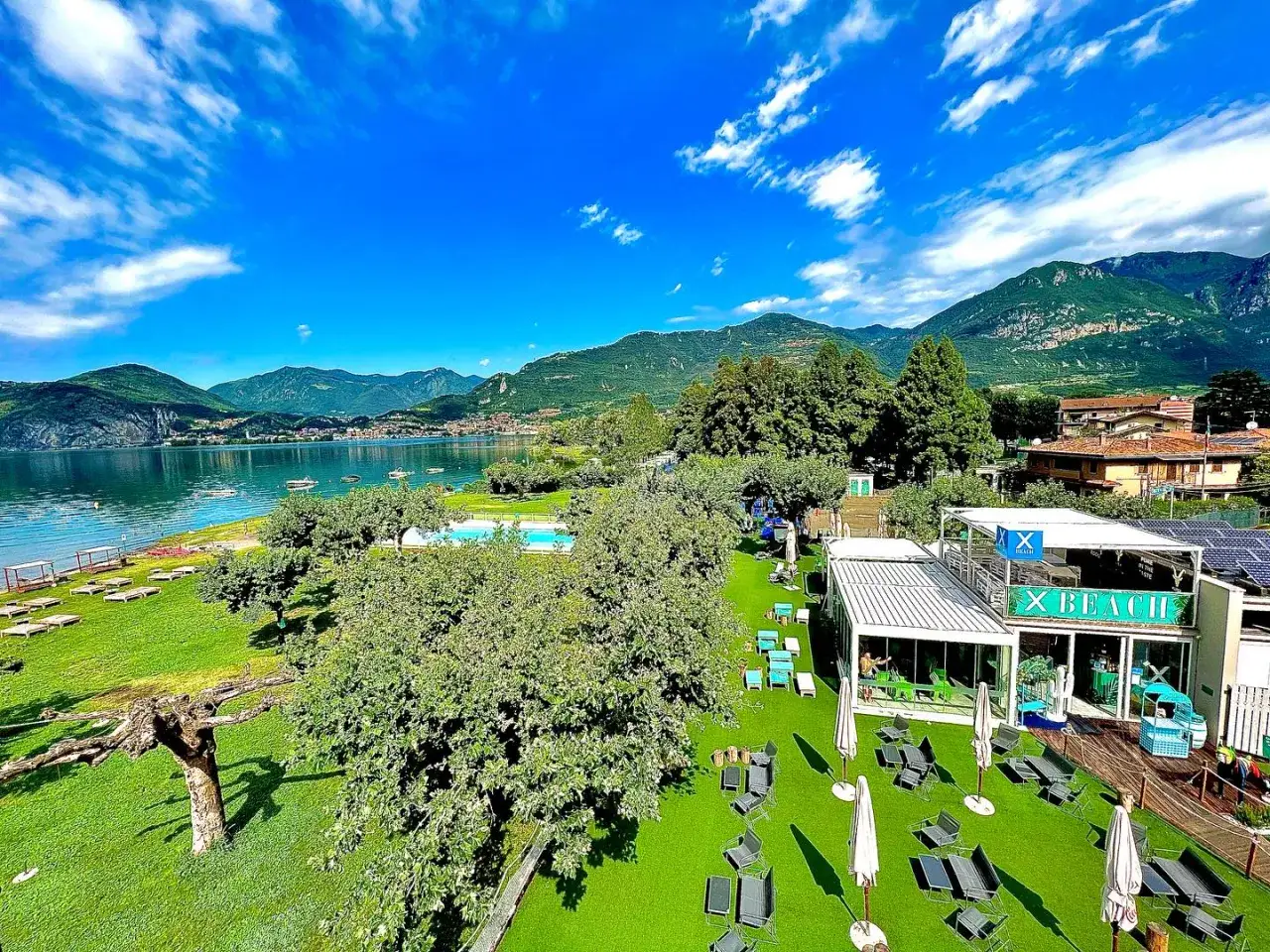 Splendida giornata alla spiaggia di Paratico, con lago, montagne e un'area relax con piscina e bar.