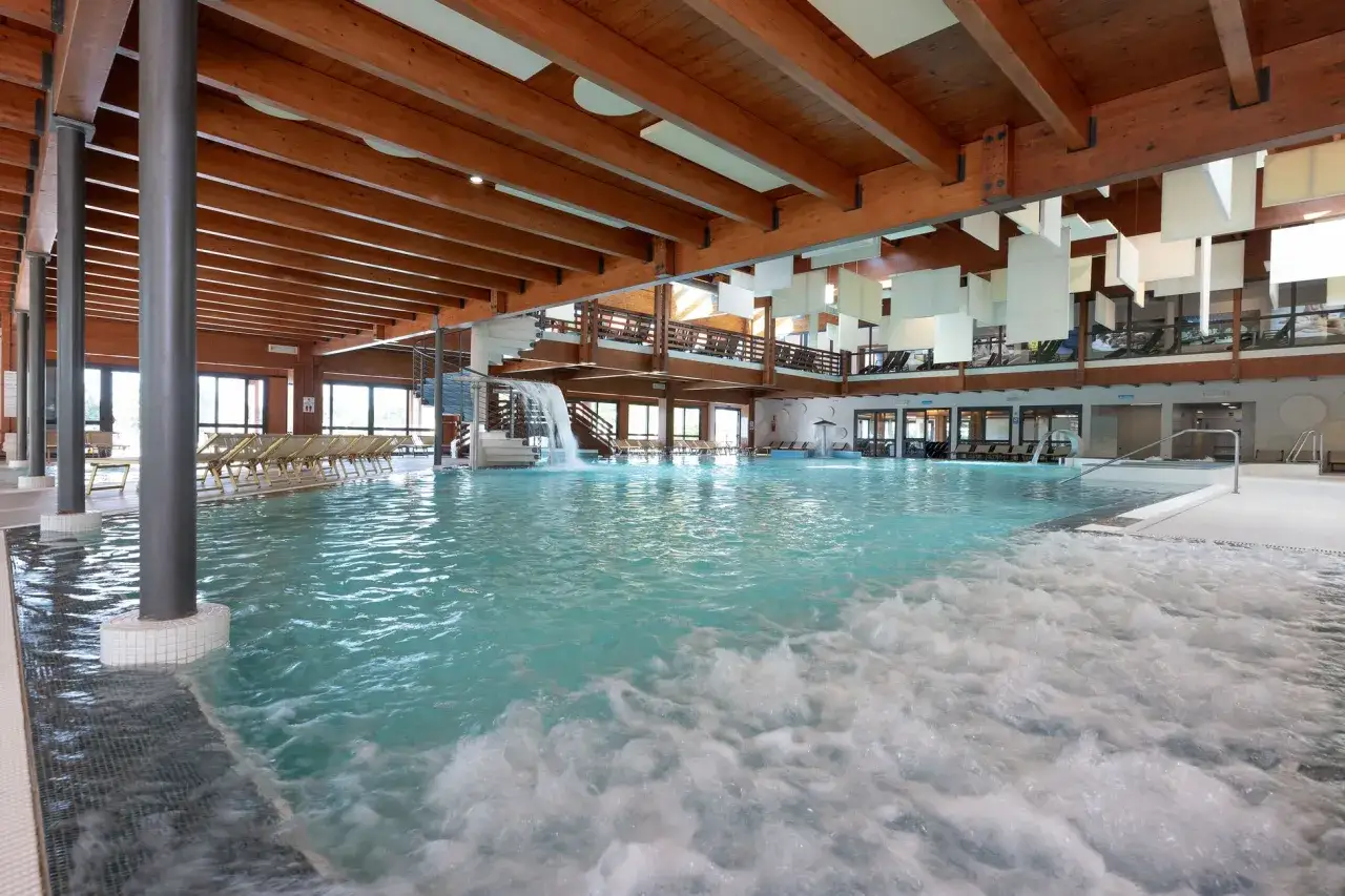 Piscina interna con cascata e idromassaggio, un'oasi di relax alle terme di Bibione.