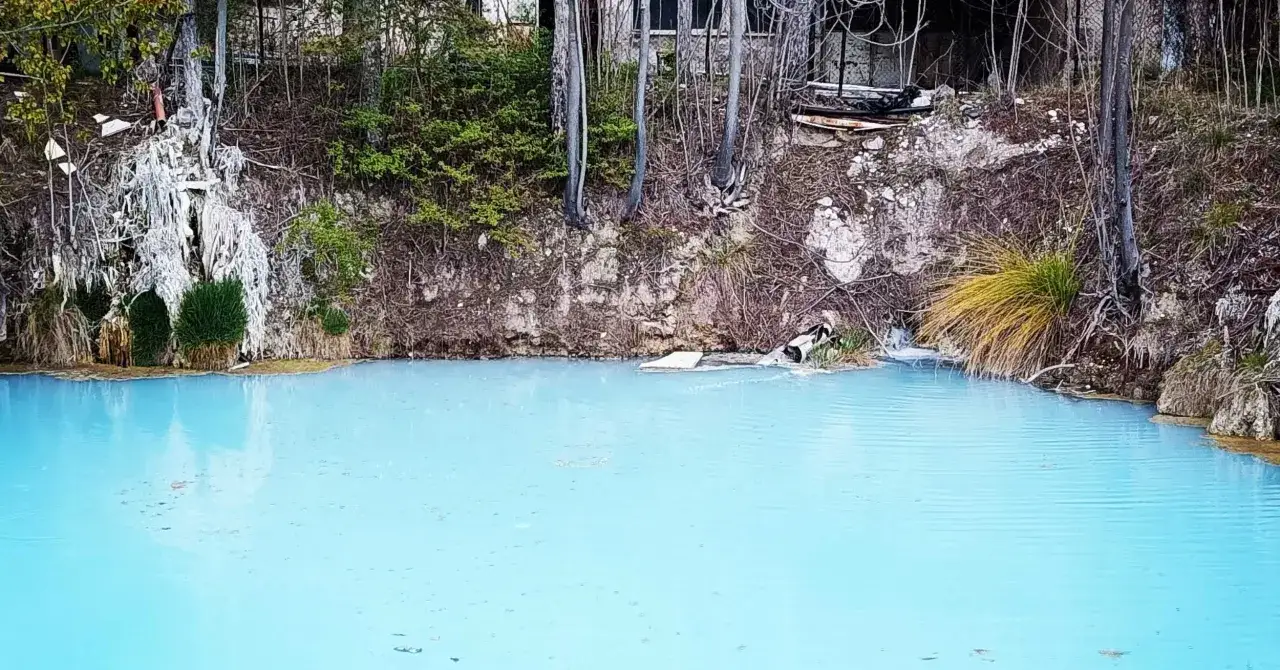 Acque azzurre e cristalline delle terme di Cotilia, con vegetazione rigogliosa e rocce circostanti.