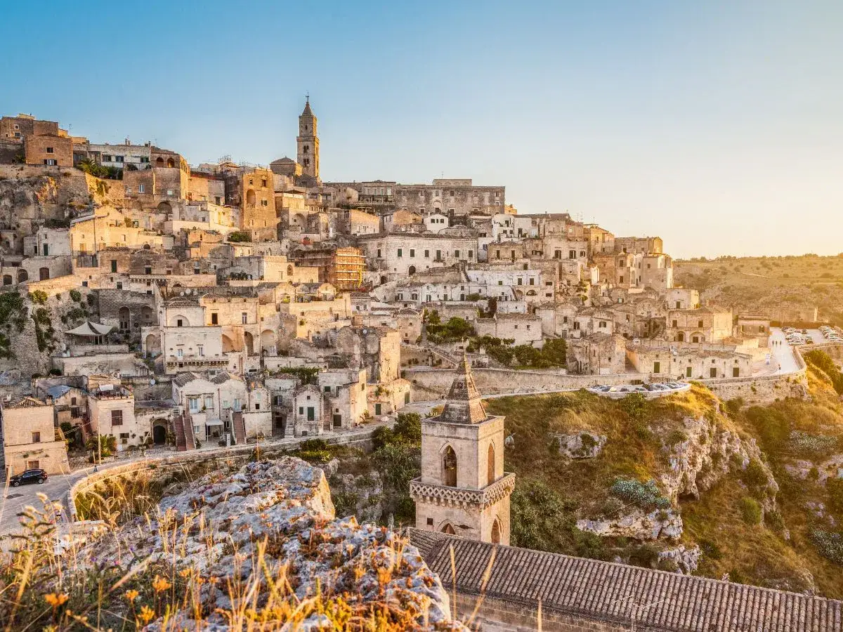 Antichi borghi in Basilicata, Matera illuminata dal sole al tramonto, un paesaggio mozzafiato scolpito nella roccia.