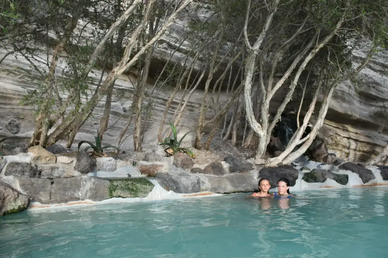 Due bambine si godono le terme libere a Ischia, immerse in acque turchesi tra rocce e vegetazione.